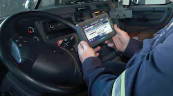 Closeup of driver holding ELD in cab of truck