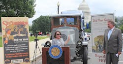 Jodie Teuton, chairwoman of the American Truck Dealers (ATD), explains opposition to the Federal Excise Tax. She stands in front of a Mack truck from the World War I era when FET was implemented. Rep. Doug LaMalfa looks on.