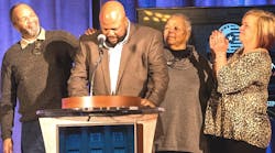 Transition Trucking award winner Joseph H Campbell, at podium, speaks during a special ceremony in Washington DC as, from left to right, father Joseph Campbell Sr, mother Littie Campbell and wife Debra Campbell show support.