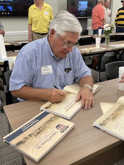 Robert H. Demere, Jr., chairman of the Colonial Group, signs copies of the book during the luncheon. Robert H. Demere, Jr., chairman of the Colonial Group, signs copies of the book during the luncheon.