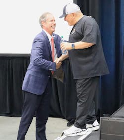 Herb Evans shakes hands with Rudy Ruettiger, keynote speaker for Tank Truck Week 2023 and the Notre Dame football player who inspired the 1993 film Rudy.