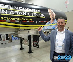 Dave Powell stands with the NTTC branding campaign trailer wrap bearing his image during Tank Truck Week 2023.