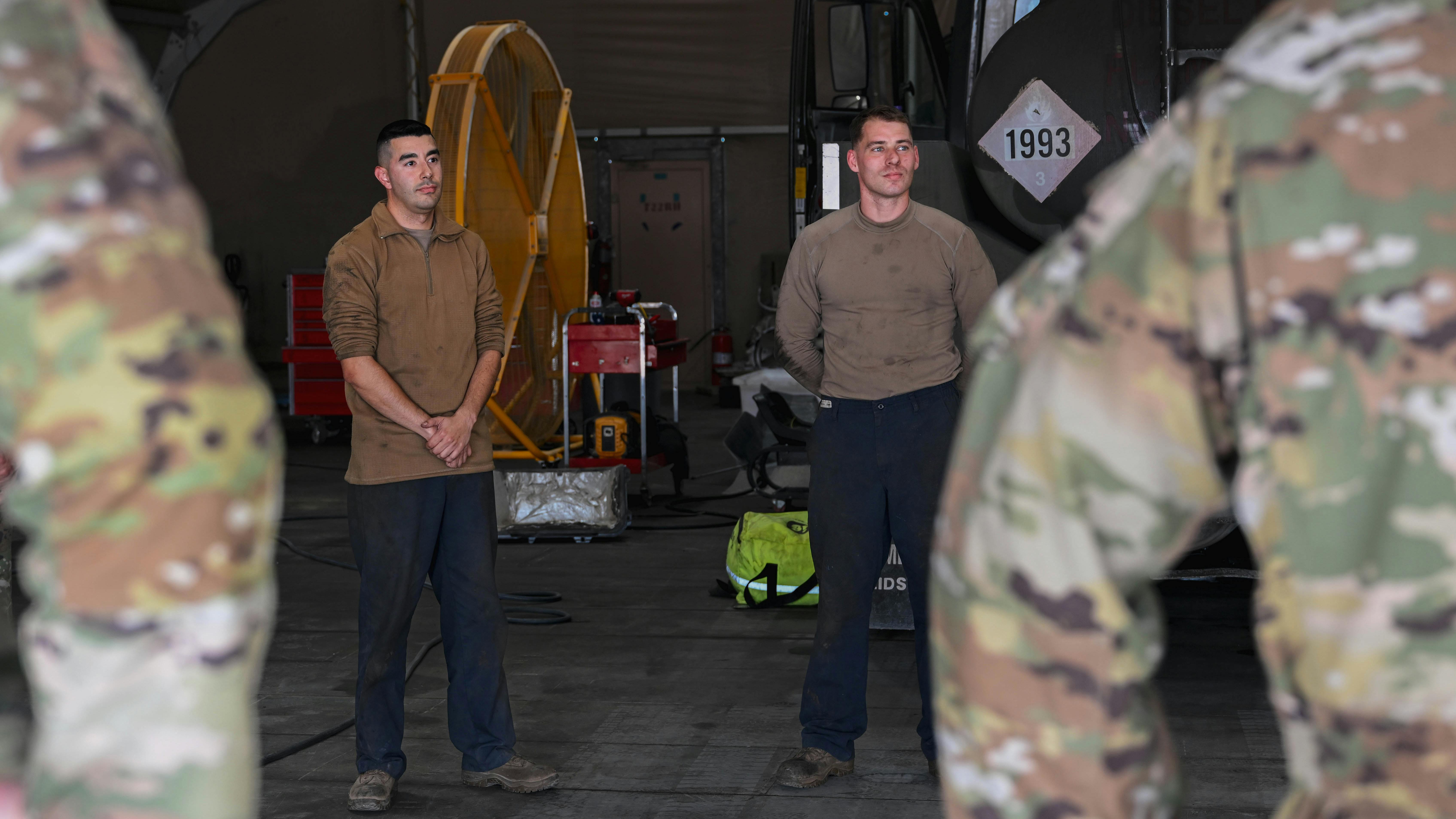 U.S. Air Force Staff Sgt. Justin Vigil, at left, and Senior Airman Samuel Marranca, both 386th Expeditionary Logistics Readiness Squadron vehicle management specialists, stand ready to be recognized by wing leadership within the U.S. Central Command area of responsibility. The Airmen were recognized for completing a critical engine swap and pumping system overhaul that returned an R-11 fuel truck to service.