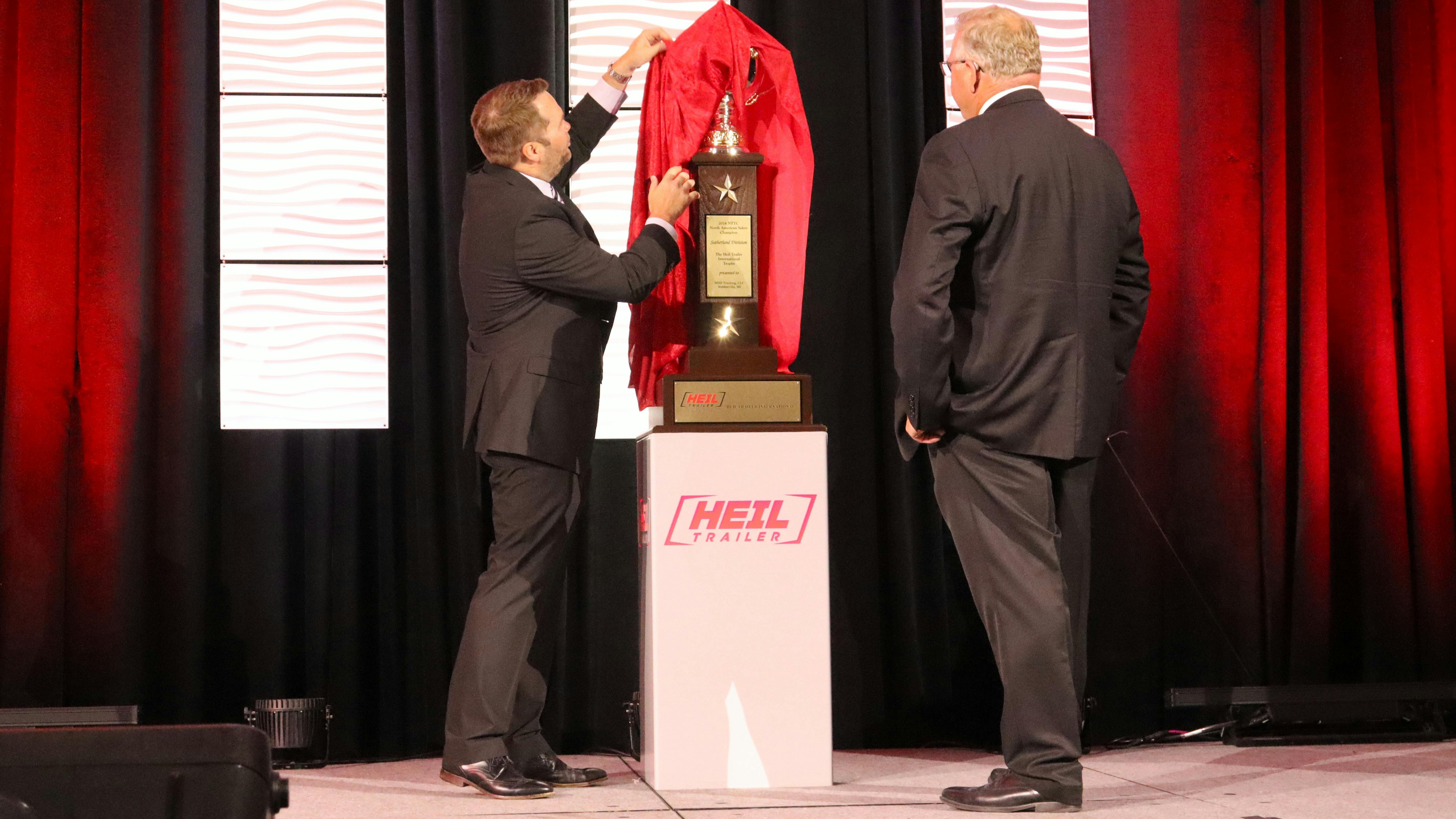 EnTrans CEO Ryan Rockafellow reveals the Sutherland divison Heil trophy as MBH Trucking CEO Brian Hitchcock looks on.