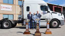 From left to right are Alex Guariento, Lance Hagler, and Bill Marchbank, who are standing behind Trimac's first three outstanding performance trophies outside the carrier's U.S. headquarters in the Houston area.